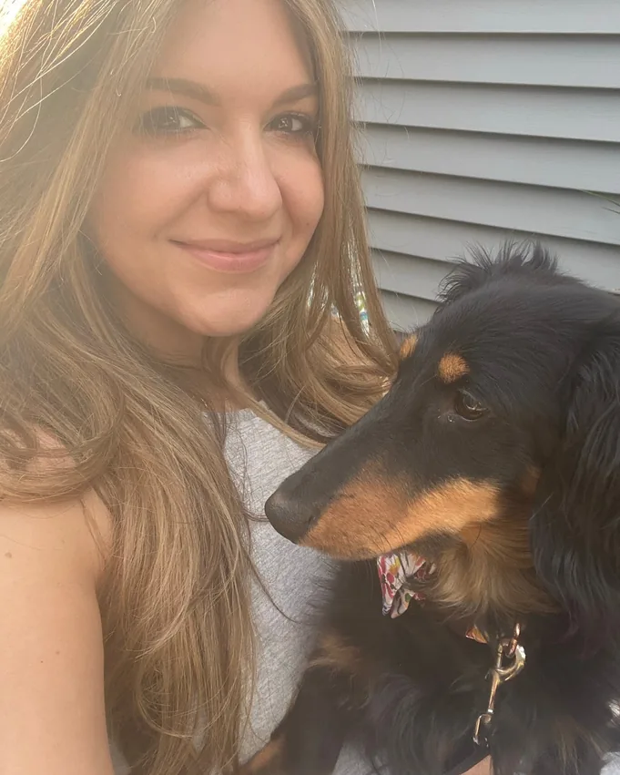 Lisa, the artist behind Doxie Vibe, outdoors with her long-haired dachshund
