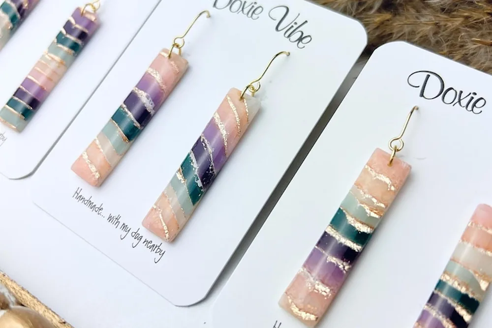 Striped clay bar earrings in pink, sage and lilac with gold lines, on Doxie Vibe display cards
