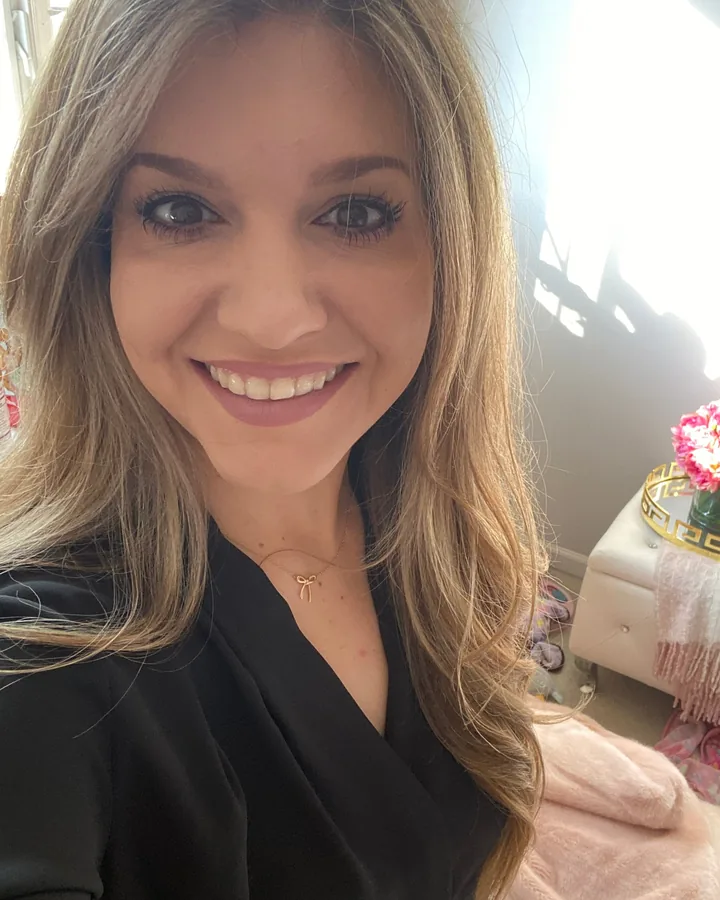 Lisa smiling, with long blonde hair and a black top